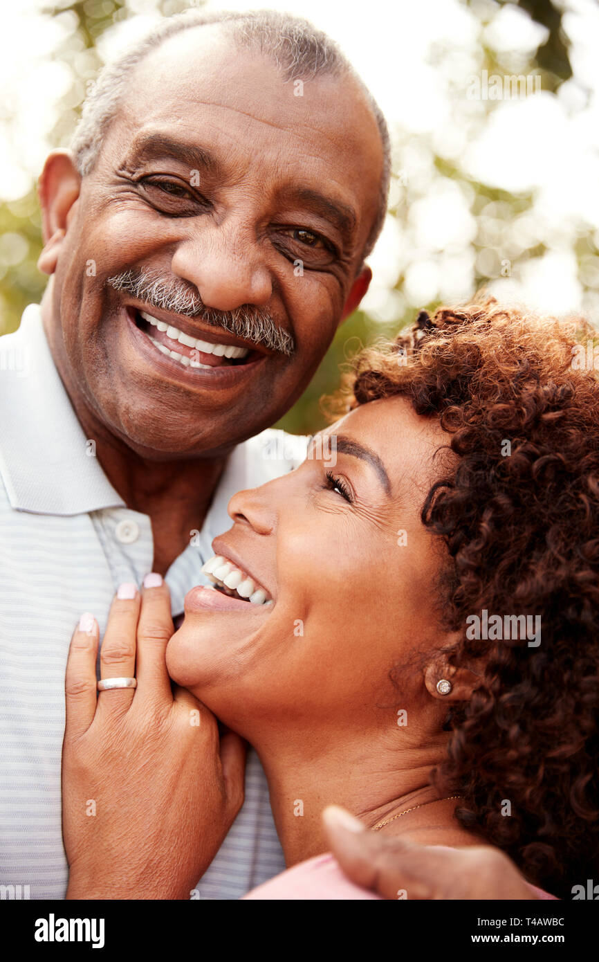 Senior uomo nero e la sua età middled figlia abbracciando e ridere, verticale Foto Stock