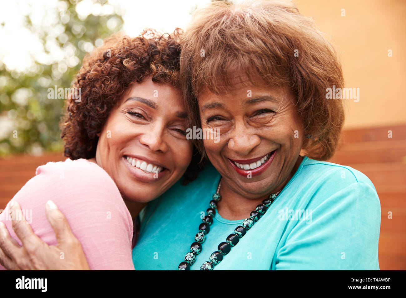 Senior mamma nero e il suo centro di età figlia sorriso alla telecamera abbracciando, close up Foto Stock