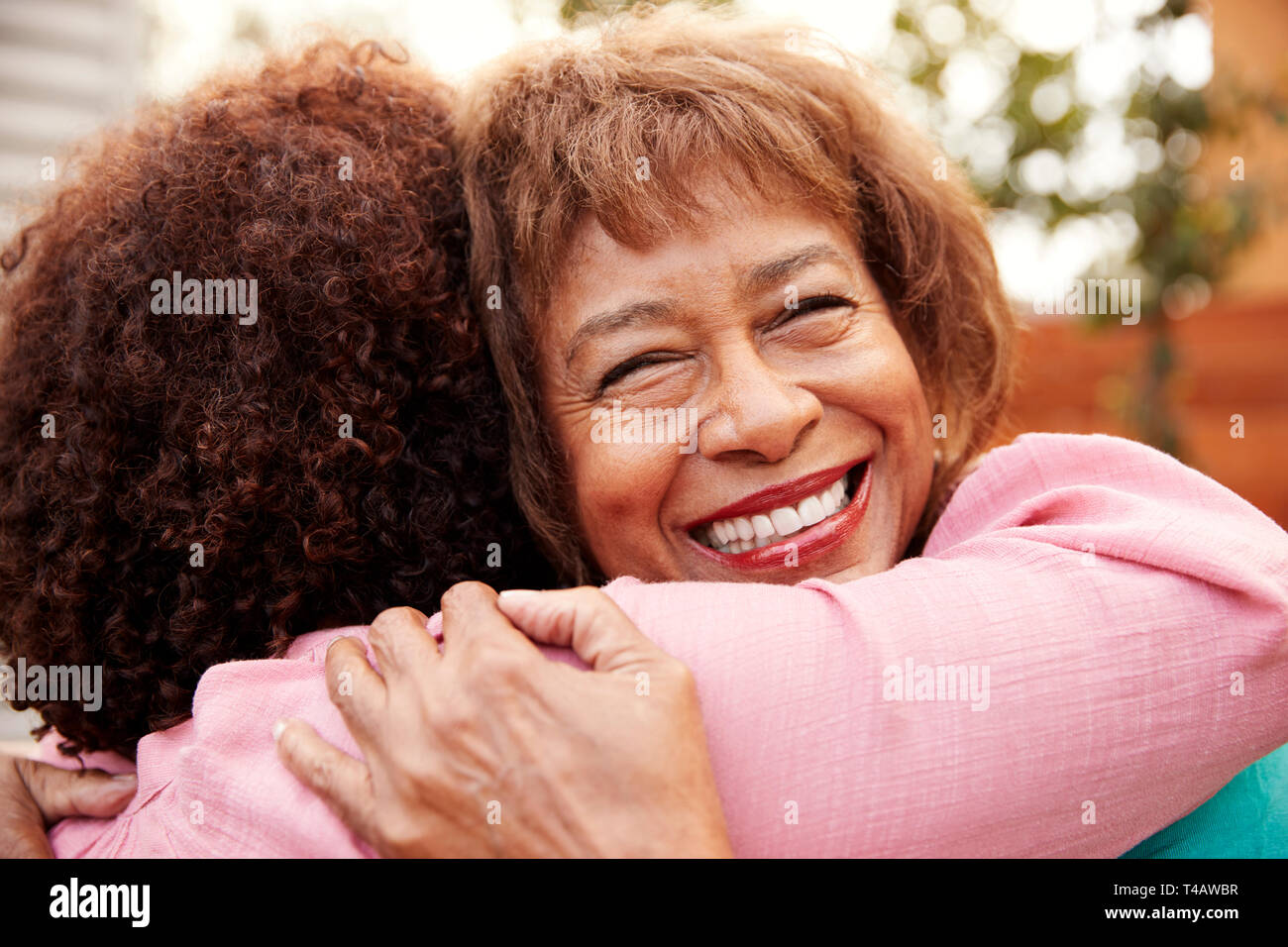 Senior mamma nero e il suo centro di età figlia abbracciando all'aperto, vicino fino Foto Stock