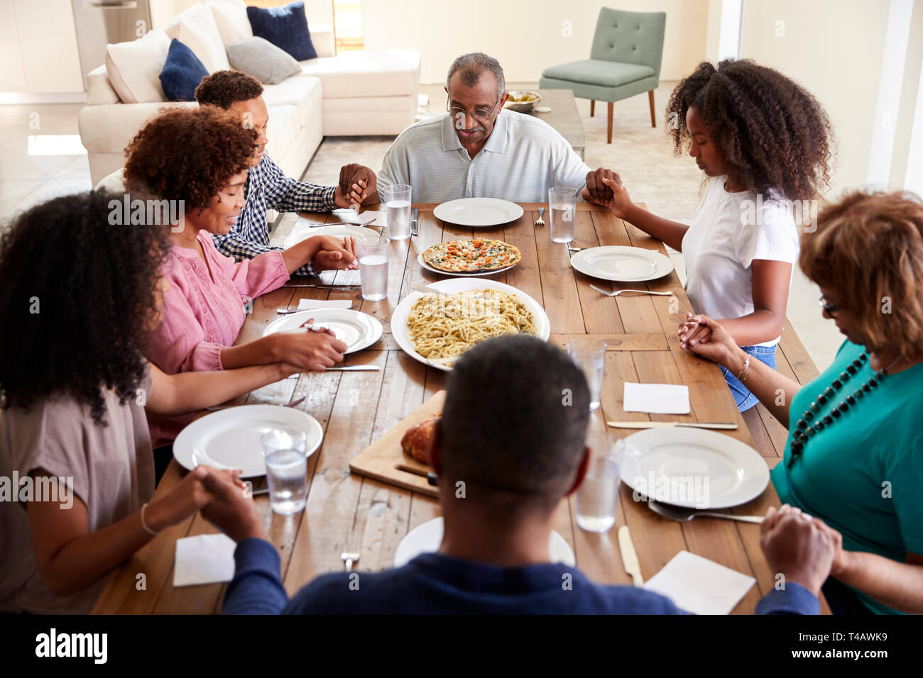 Tre generazioni della famiglia nero tenendo le mani e dire grazia a tavola prima di cena,vista in elevazione Foto Stock