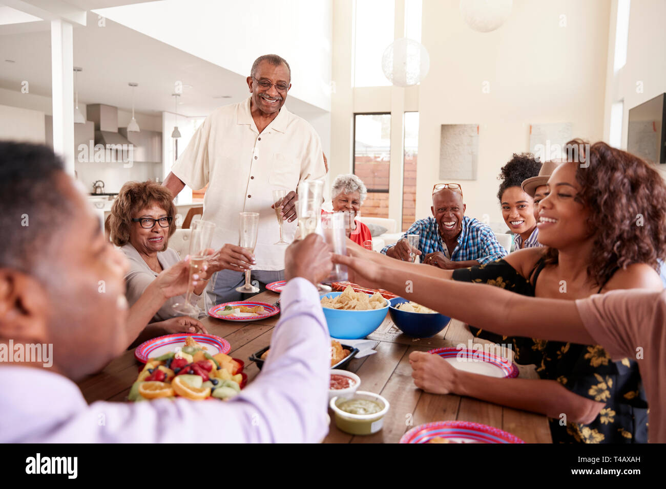 Nonno in piedi per fare un discorso a tavola con la sua famiglia, close up Foto Stock