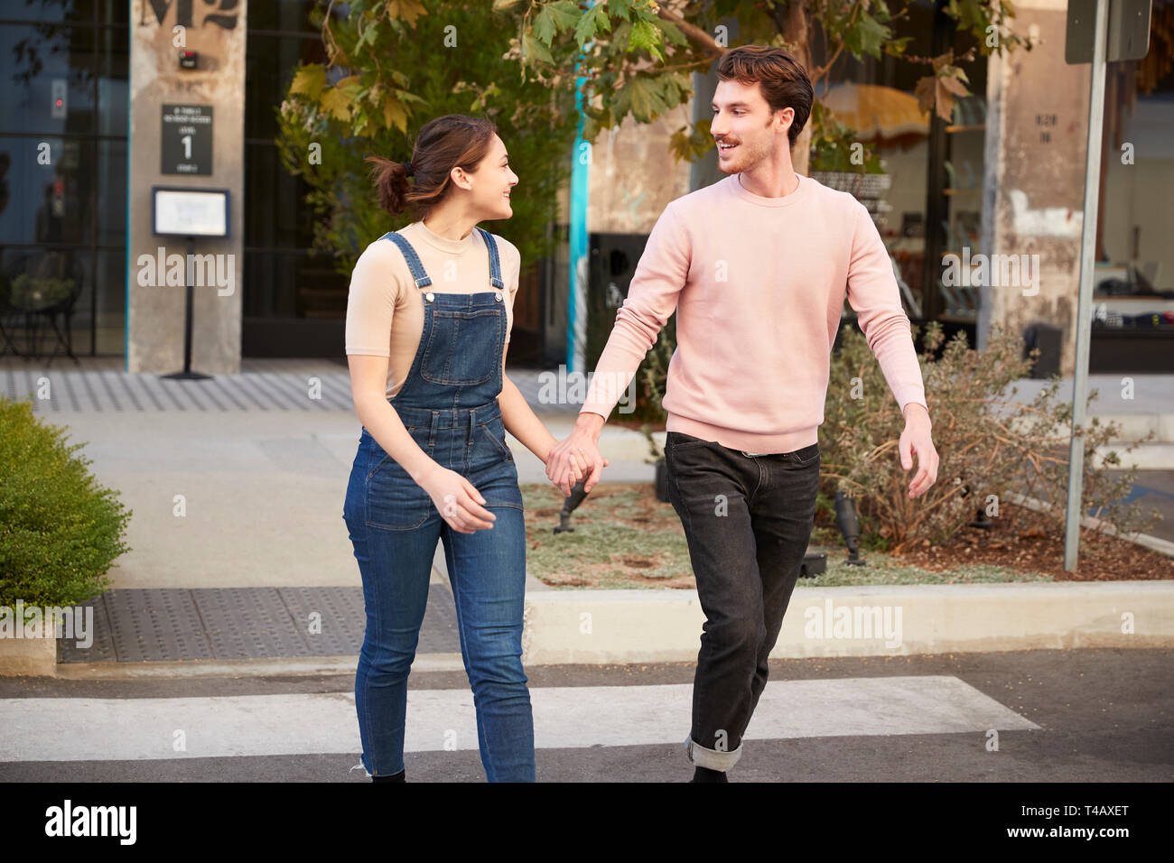 La millenaria hipster giovane attraversando la strada nella città Holding Hands, close up Foto Stock