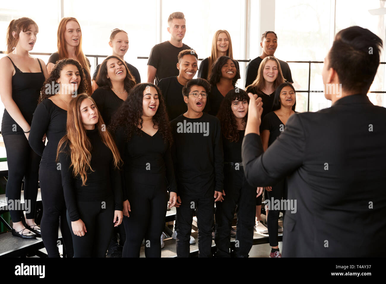 Studenti maschi e femmine a cantare in coro con insegnante a Performing Arts School Foto Stock