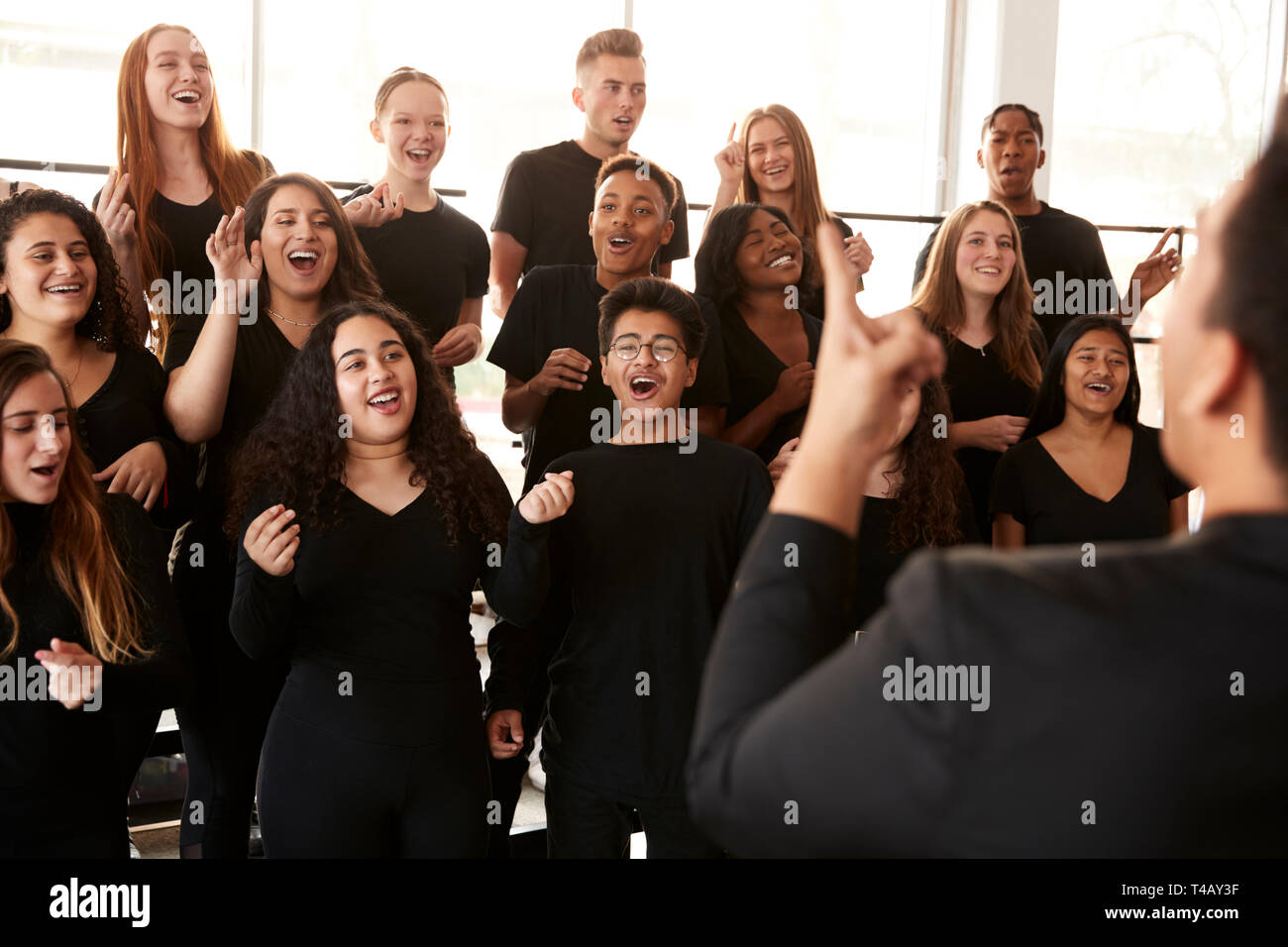 Studenti maschi e femmine a cantare in coro con insegnante a Performing Arts School Foto Stock