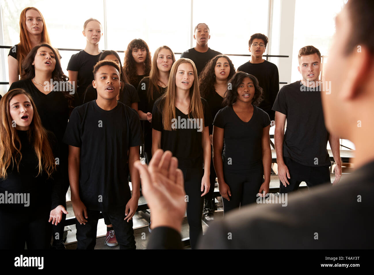 Studenti maschi e femmine a cantare in coro con insegnante a Performing Arts School Foto Stock
