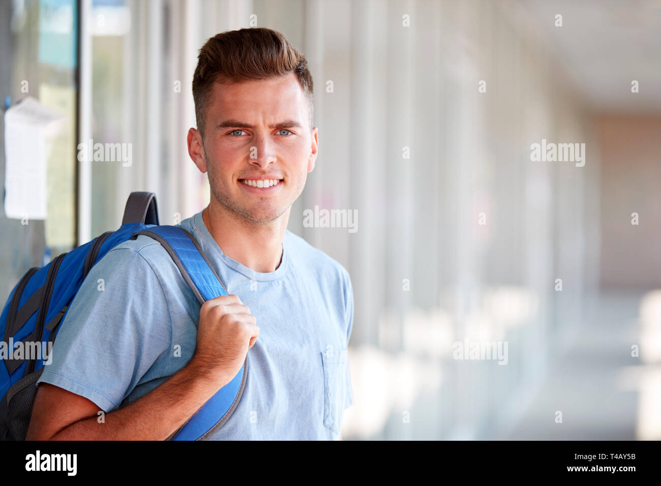 Ritratto di sorridere maschio Studente universitario con zaino in corridoio del Collegio di costruzione Foto Stock
