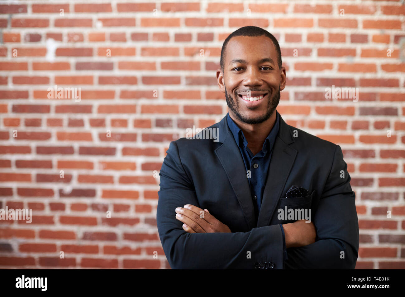 Ritratto di imprenditore in piedi contro un muro di mattoni in ufficio moderno Foto Stock
