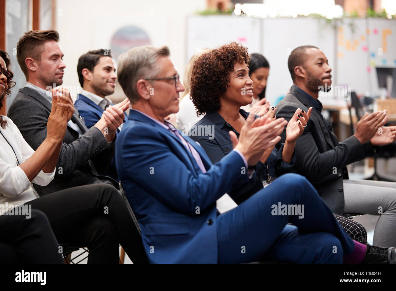Un gruppo di imprenditori e imprenditrici applaudire la presentazione alla conferenza Foto Stock