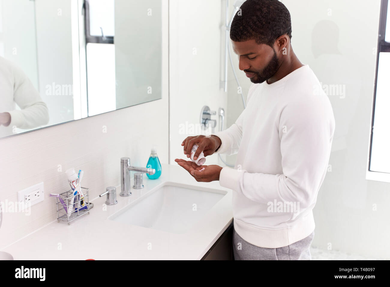 L'uomo in bagno tenendo integratore vitaminico compresse Foto Stock