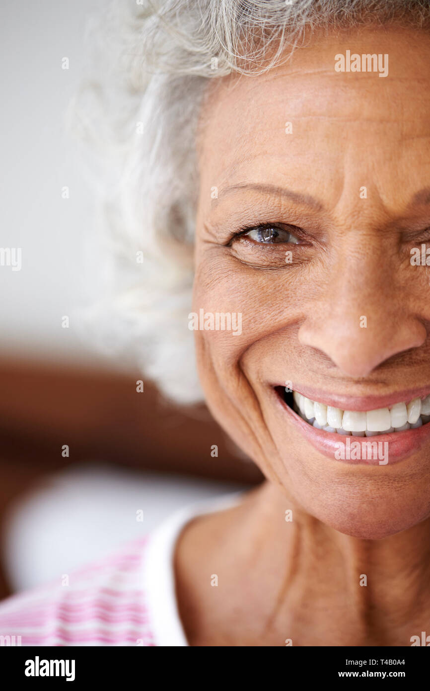Tagliato di testa e spalle Ritratto di sorridere Senior donna seduta sul letto di casa cercando positivo Foto Stock