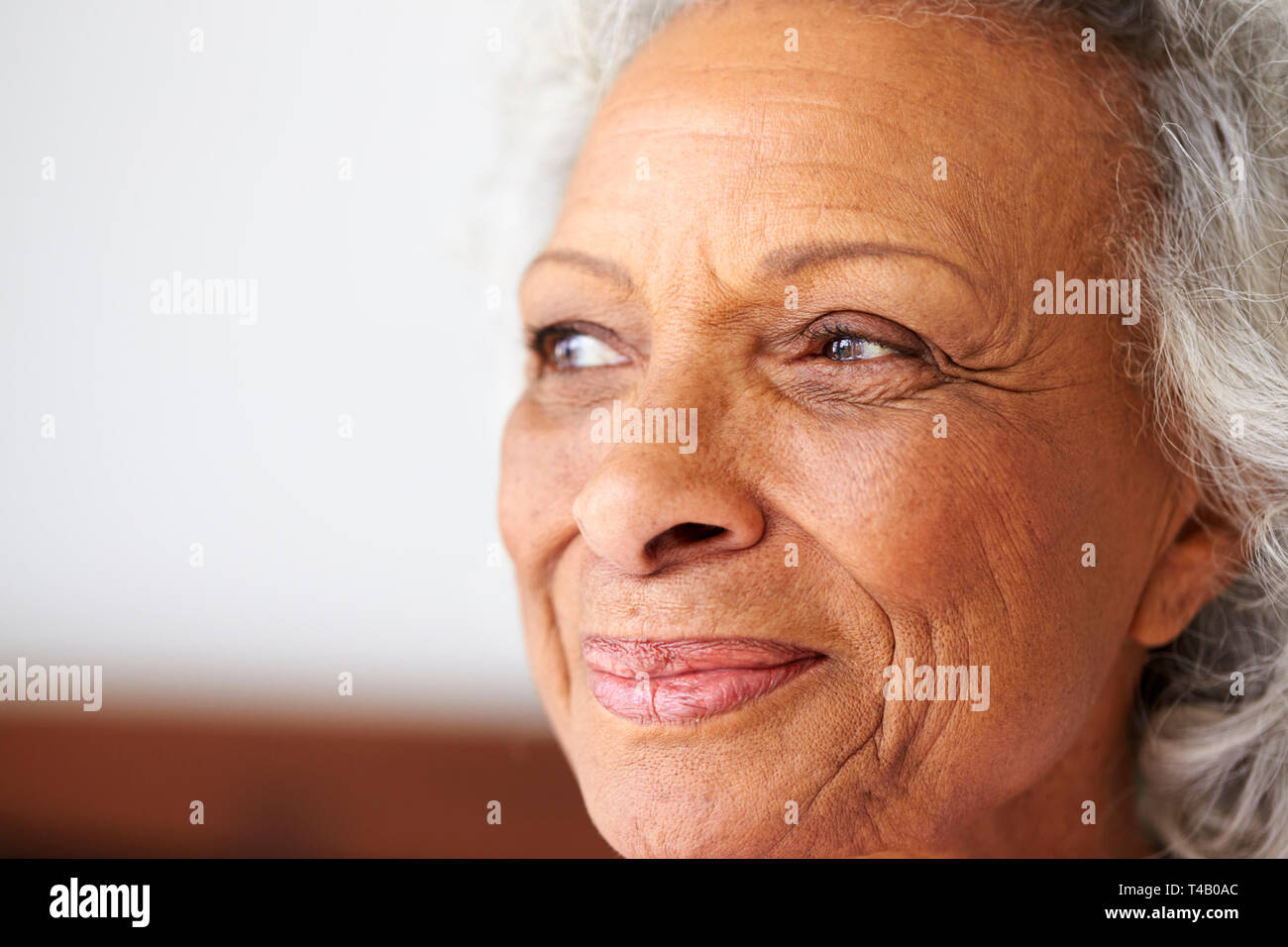 Close Up di sorridere Senior donna seduta sul letto di casa cercando positivo Foto Stock