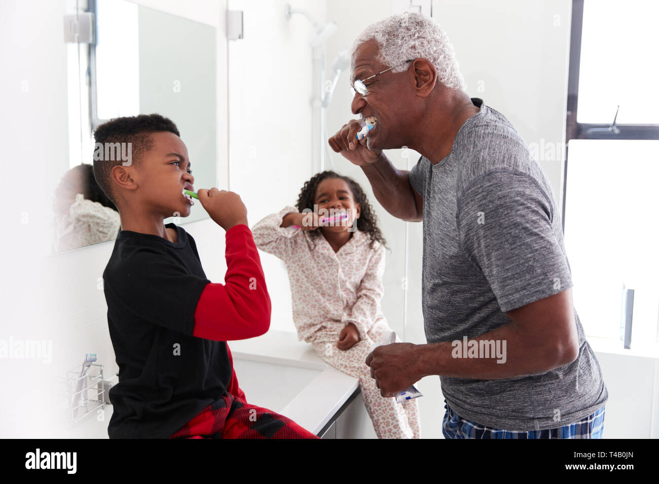 Nonno in bagno indossando pigiami spazzolare i denti con i nipoti Foto Stock