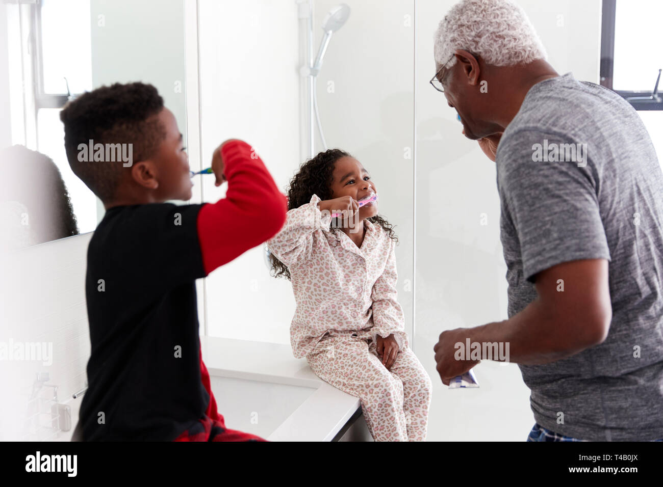 Nonno in bagno indossando pigiami spazzolare i denti con i nipoti Foto Stock