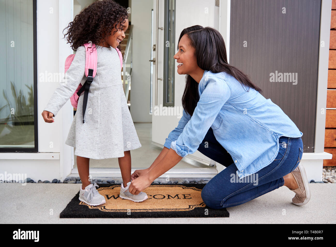 Madre Figlie di legatura lacci delle scarpe come lei lascia per la scuola Foto Stock