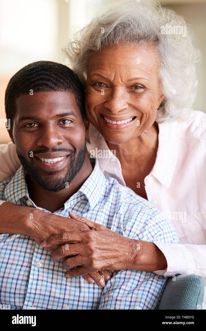 Ritratto di sorridere Senior abbracciando madre figlio adulto a casa Foto Stock