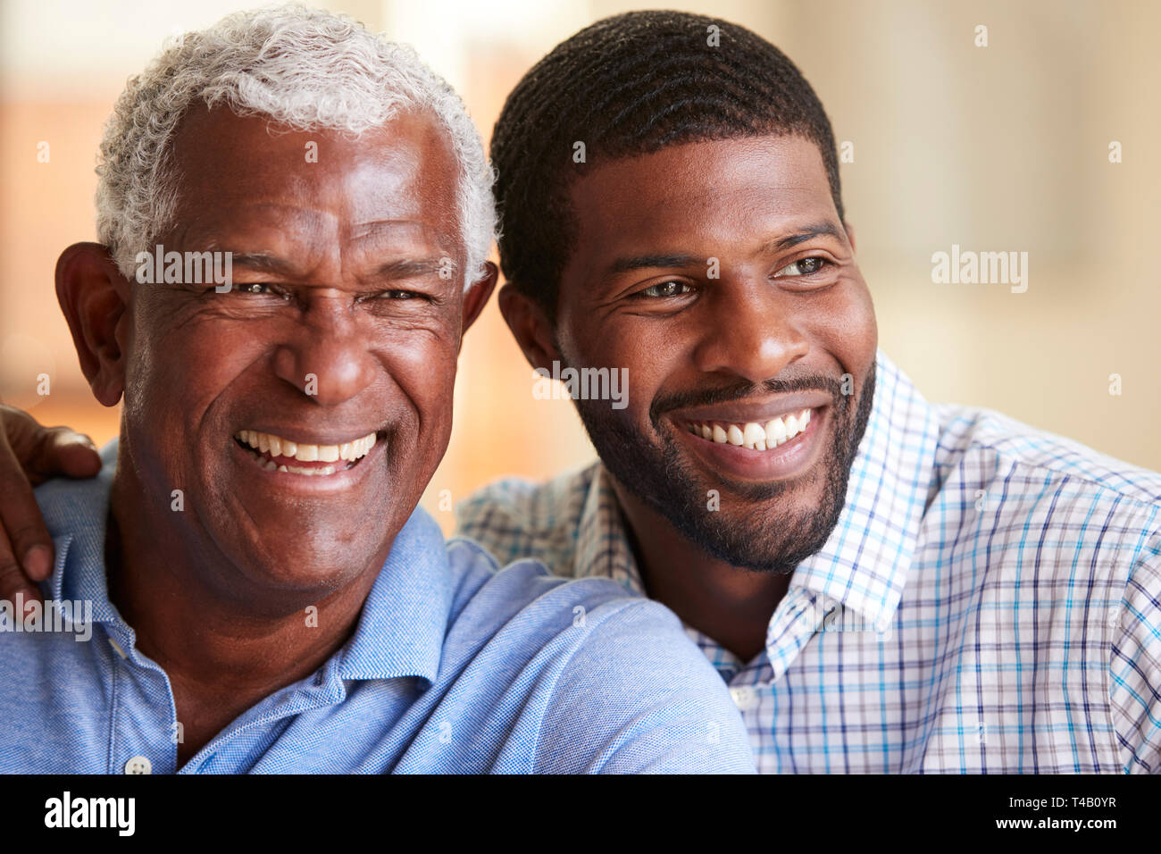 Sorridente Padre Senior essendo abbracciato dal figlio adulto a casa Foto Stock