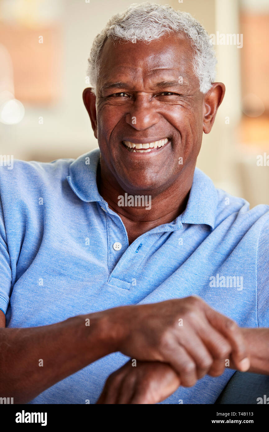 Ritratto di sorridente uomo Senior rilassante sul divano di casa Foto Stock
