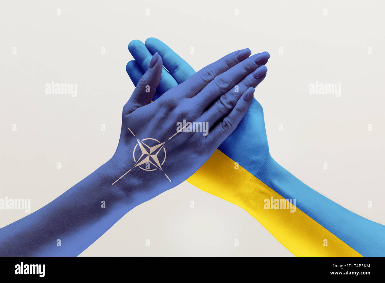 United forces, supporto. Maschio e femmina di mani colorate di bandiere di Ucraina e NATO isolato su bianco di sfondo per studio. Nozione di aiuto, il partenariato dei paesi, politico ed economico le relazioni. Foto Stock