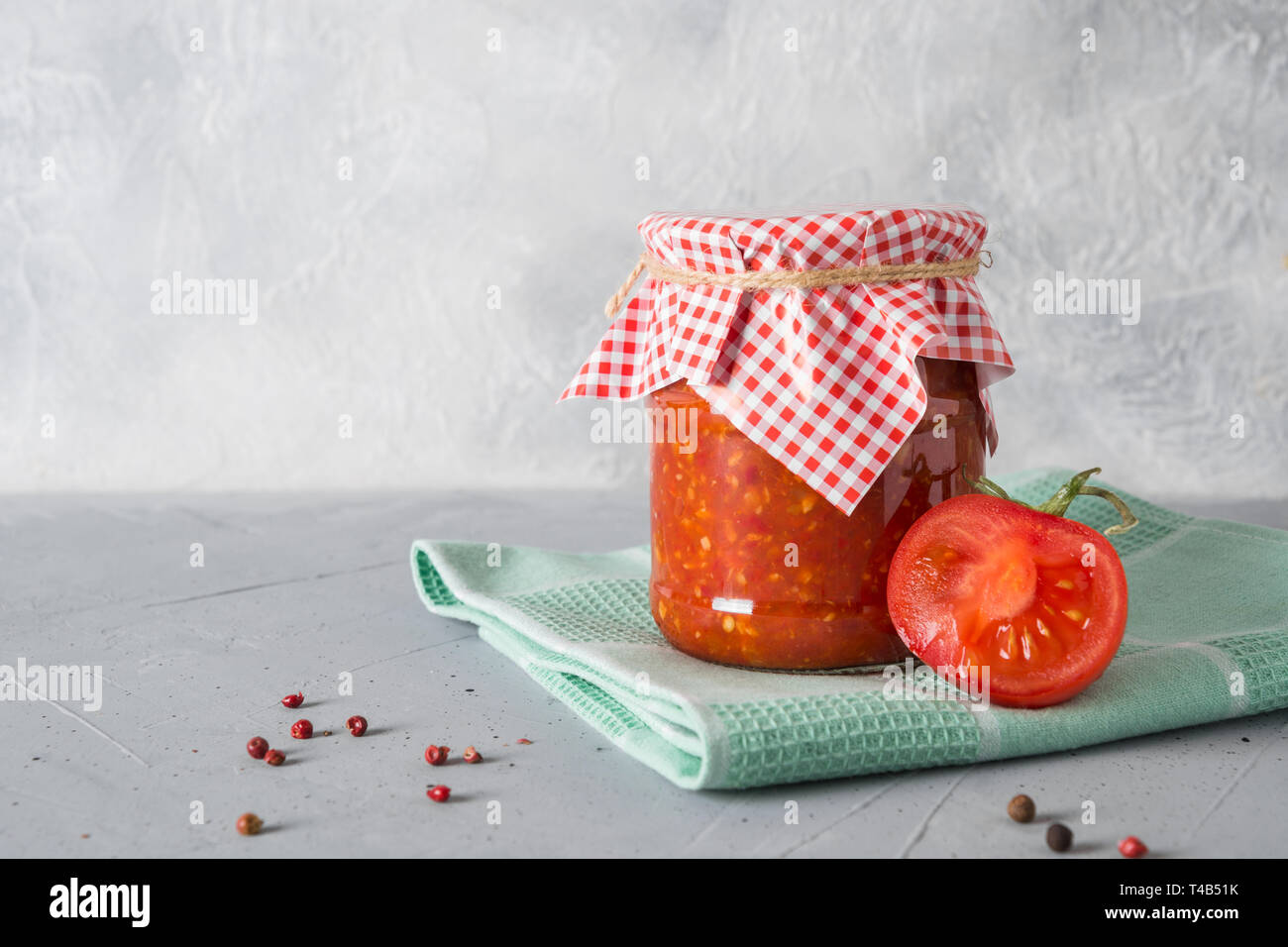 In casa ragù vegetale adjika con pomodori in vaso su sfondo chiaro. Close-up. Foto Stock