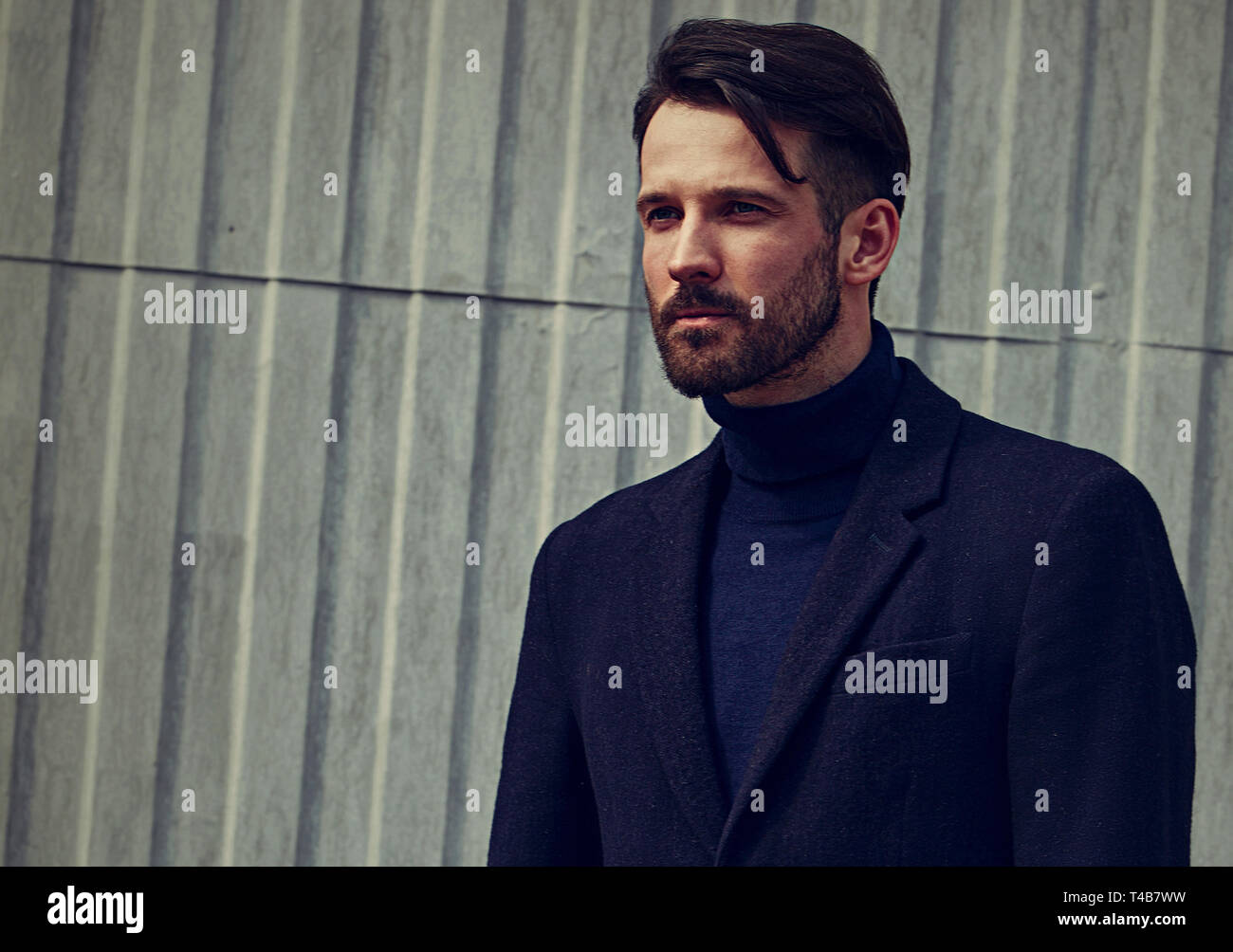 Barba di moda business stile bello modello maschile con grave aspetto concentrato in posa nello stile di abbigliamento all'esterno della parete dello sfondo. Closeup tonica portr Foto Stock