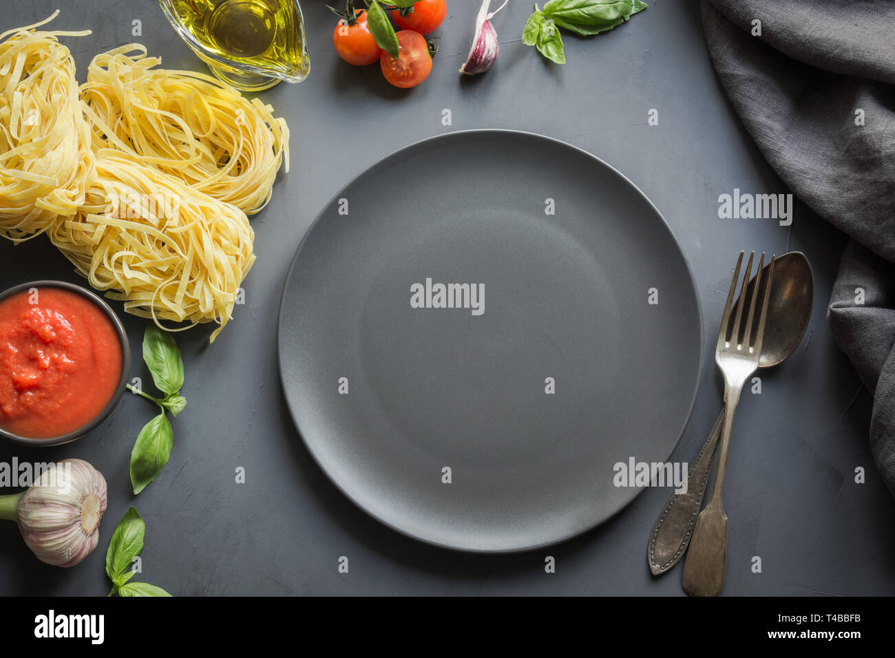 Svuotare la piastra nera e il bordo di pasta cruda, pomodori nel proprio succo, basilico, parmigiano per cucinare piatti italiani e mediterranei. Foto Stock