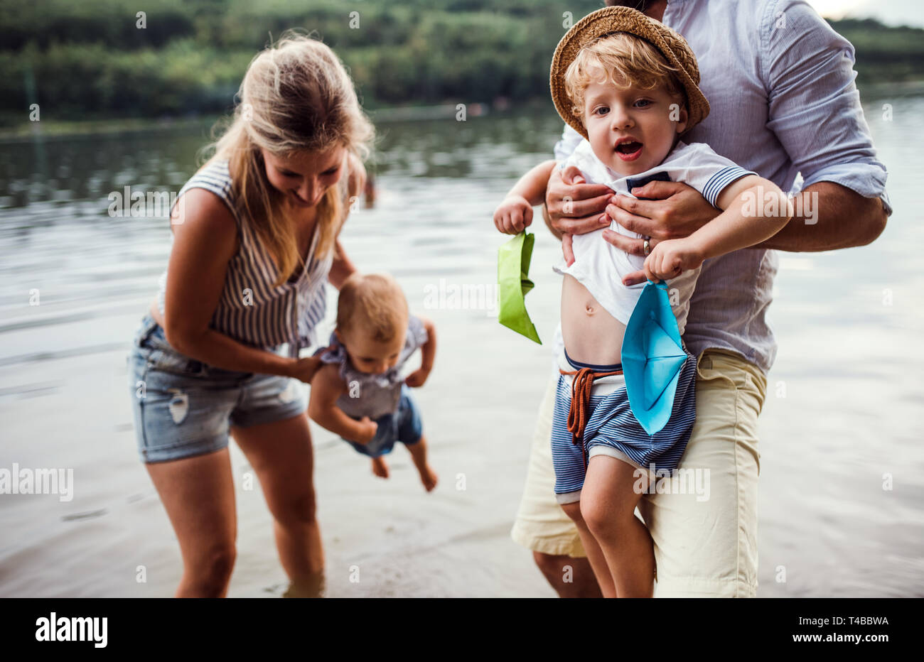 Una giovane famiglia con due bambini Bimbi all'aperto dal fiume in estate. Foto Stock
