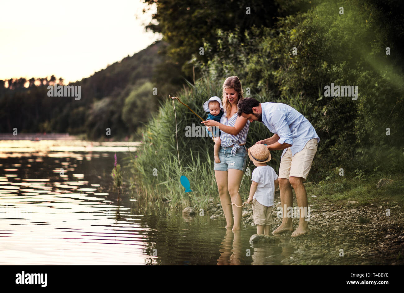 Una giovane famiglia con due bambini Bimbi all'aperto dal fiume in estate. Foto Stock