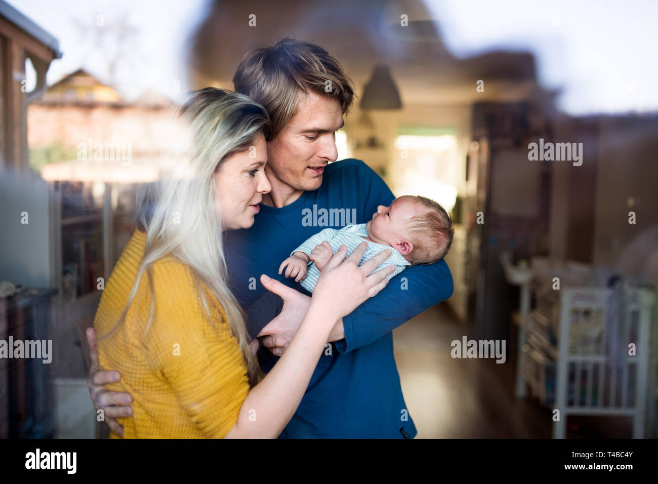 Bella giovani genitori con un neonato in casa. Shot attraverso il vetro. Foto Stock