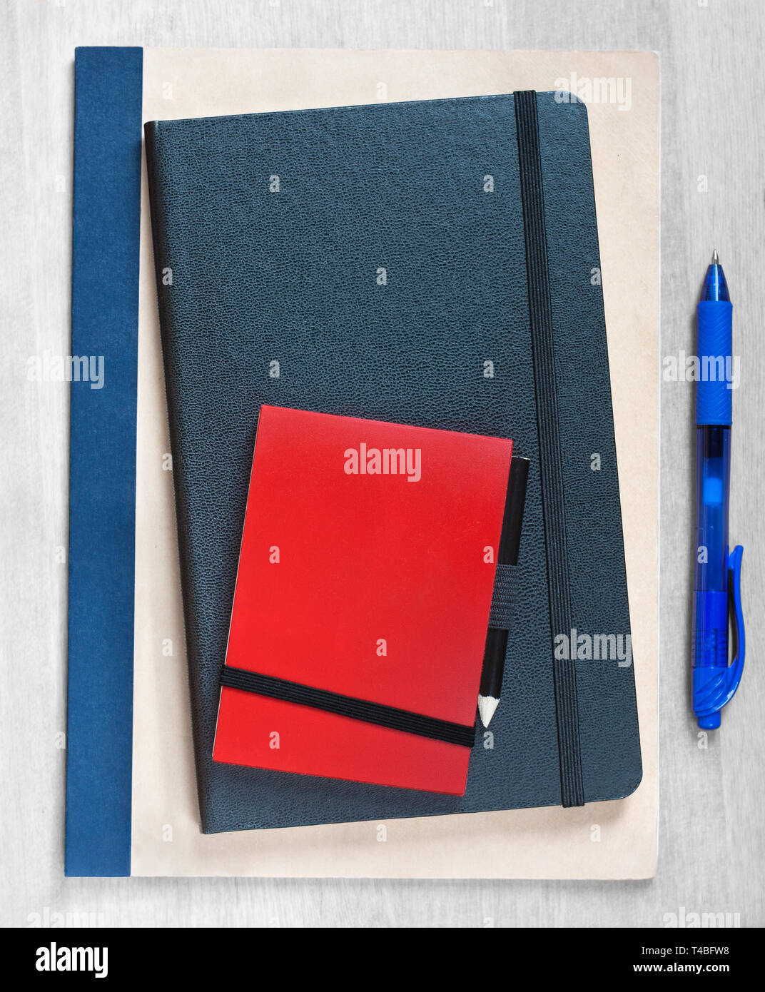 Stiamo assumendo, scritta su una pila di notebook, accanto ad una penna di colore blu su uno sfondo di legno Foto Stock