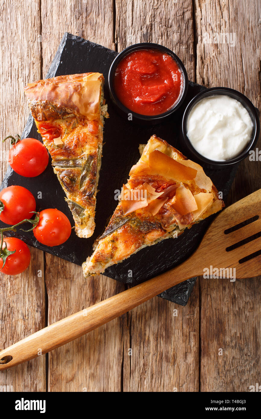 Fette di torte salate ripiene con salmone, pomodori, formaggio ed erbe vicino sul tavolo. Verticale in alto vista da sopra Foto Stock