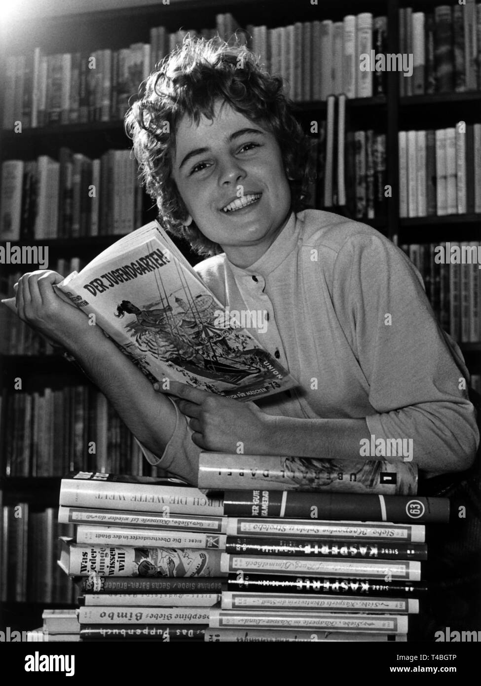 Un bookworm scava fra i libri in un book shop nel 1955. | Utilizzo di tutto il mondo Foto Stock