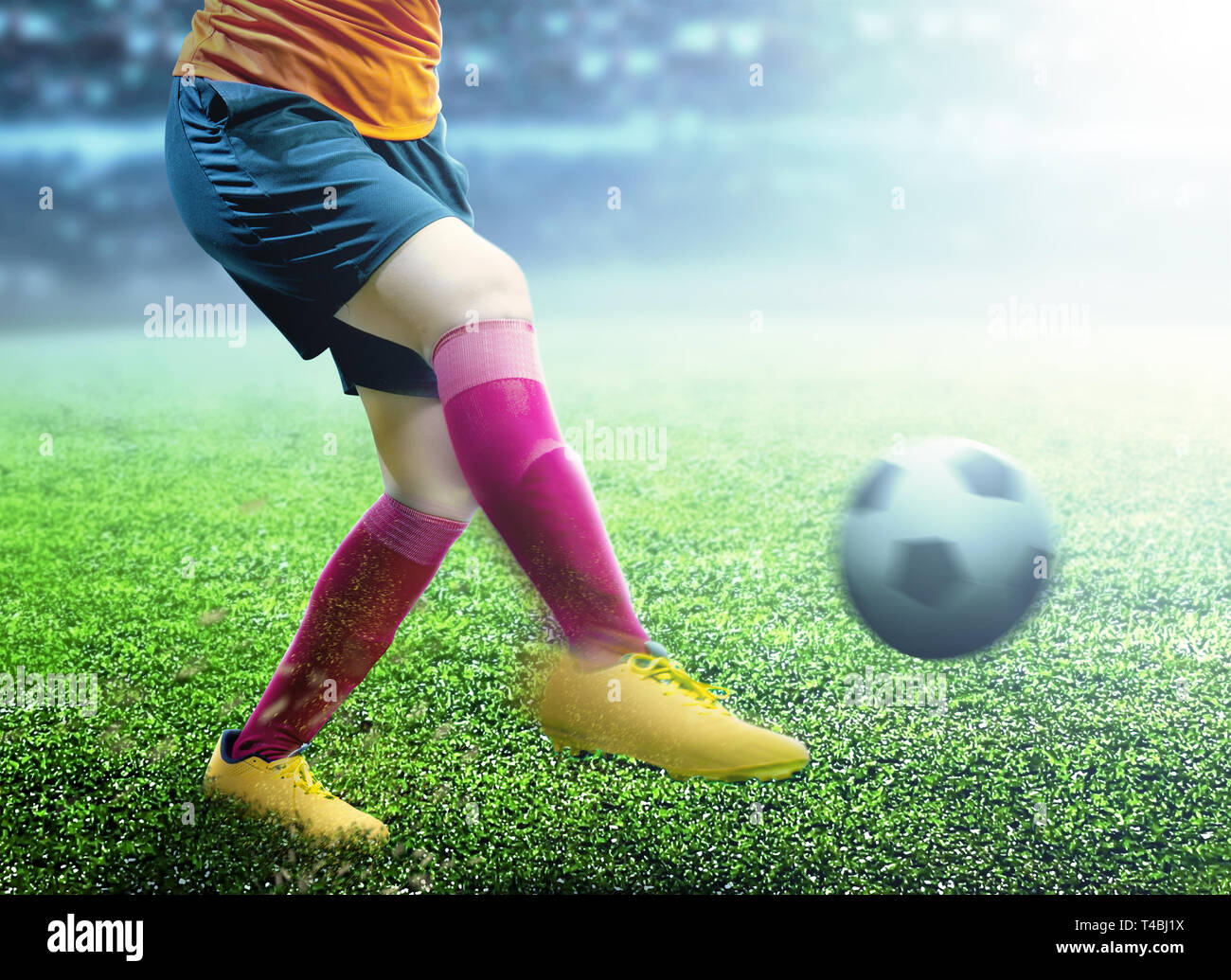 Giocatore di football donna in maglia arancione calciare la palla sul campo di calcio Foto Stock