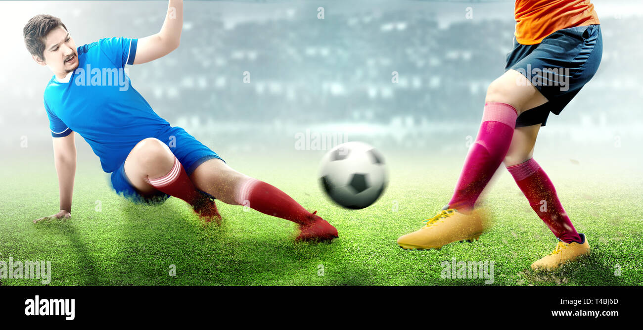 Asian giocatore di football uomo in maglia blu scivolata la palla al suo  avversario sul campo di calcio Foto stock - Alamy