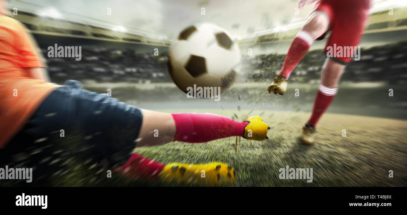 Giocatore di football uomo calciare la palla quando il suo avversario cercando di affrontare la palla sul campo di calcio a Stadium Foto Stock
