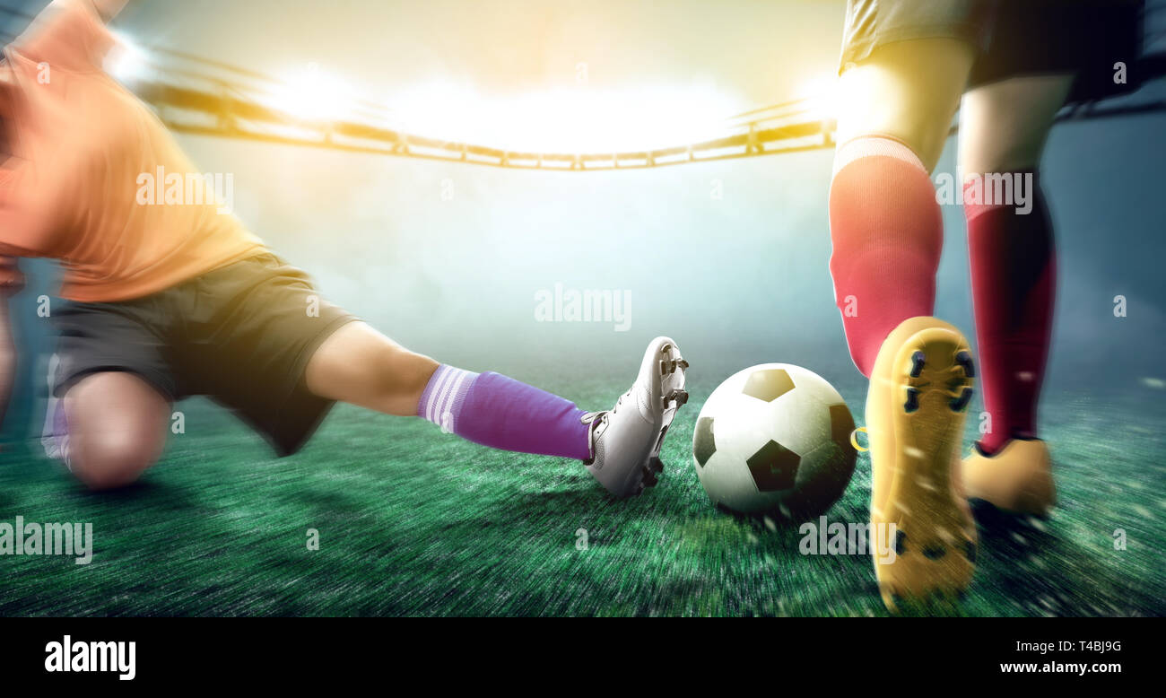 Giocatore di football donna in maglia arancione scivolata la palla al suo avversario sul campo di calcio a Stadium Foto Stock