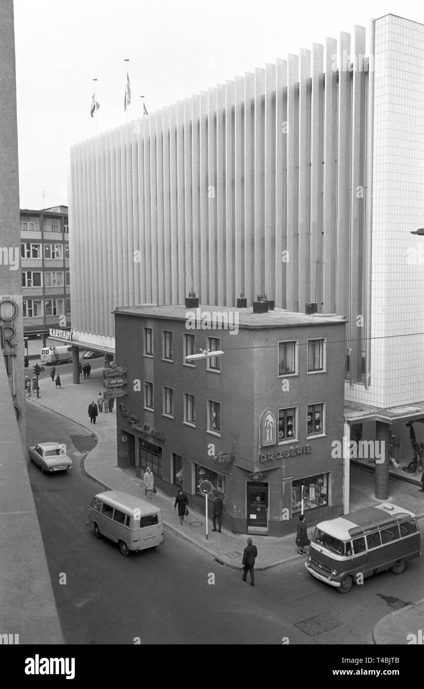 Un piccolo magazzino che ospita una macelleria, un ristorante e un negozio di farmaco, sorge accanto a un grande department store di Colonia città interna (archivio foto dal XII di novembre nel 1963). | Utilizzo di tutto il mondo Foto Stock