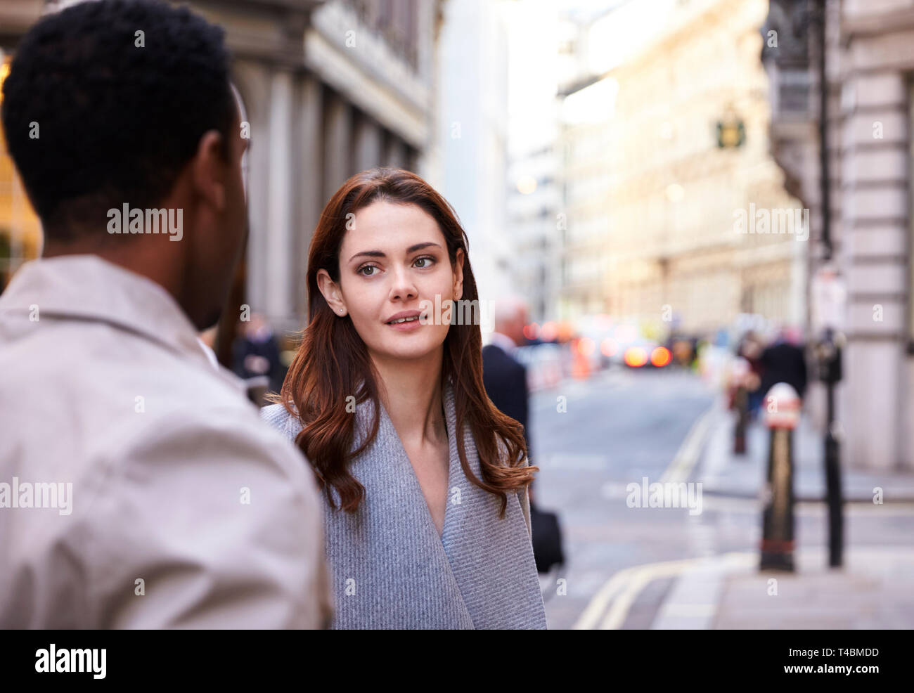 La millenaria colleghi di lavoro in piedi su una strada di Londra avente una conversazione, close up Foto Stock