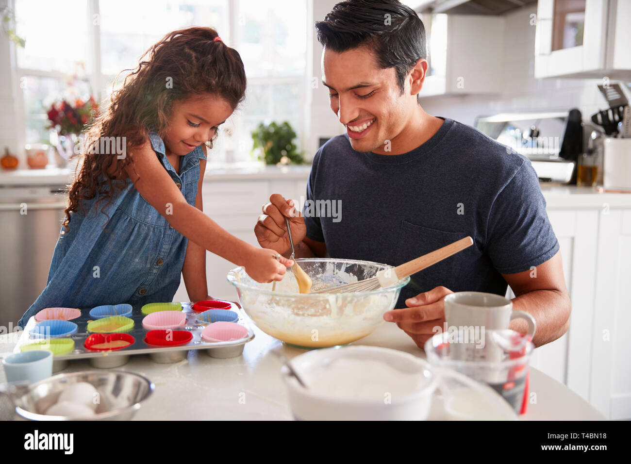 Ragazza giovane permanente al tavolo della cucina la preparazione di un preparato per torte con suo padre, close up Foto Stock