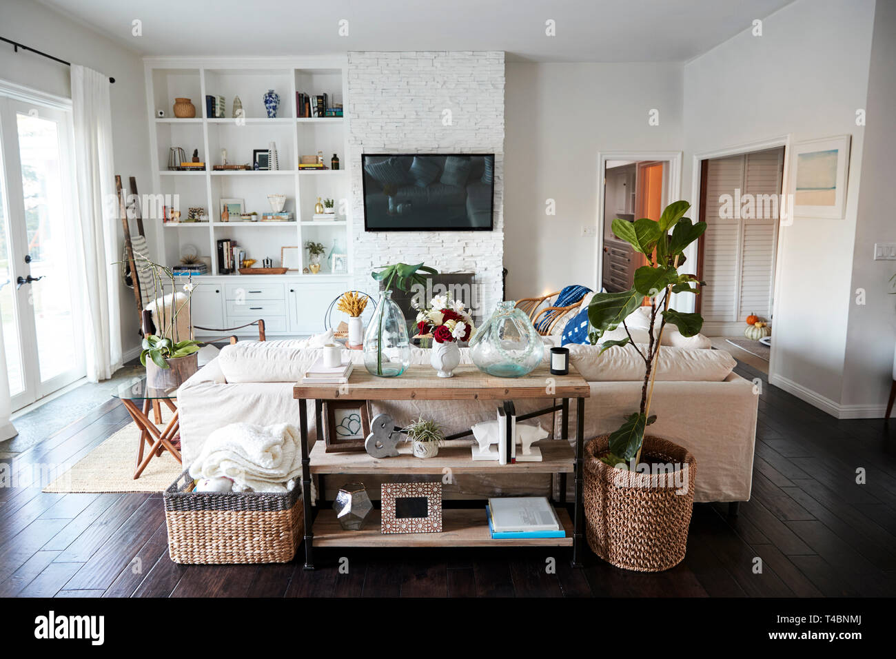 Un salotto con pareti bianche e legno scuro tavoloni visibile in pieno giorno, da dietro il divano che si trova in una posizione centrale, nessun popolo in shot Foto Stock