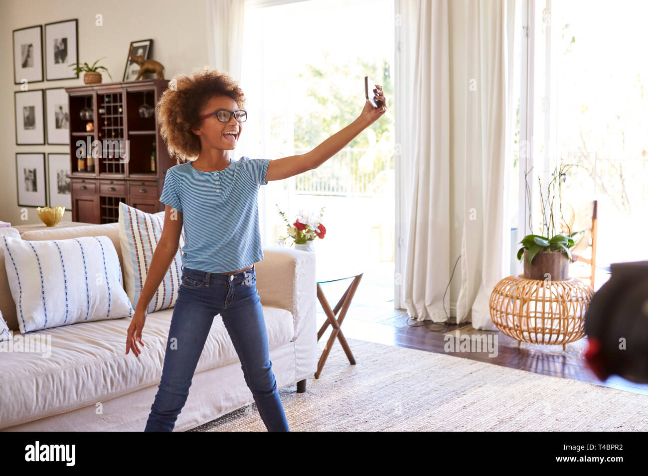 Pre-teen ragazza cattura se stessa cantando utilizzando un social media app sullo smartphone Foto Stock