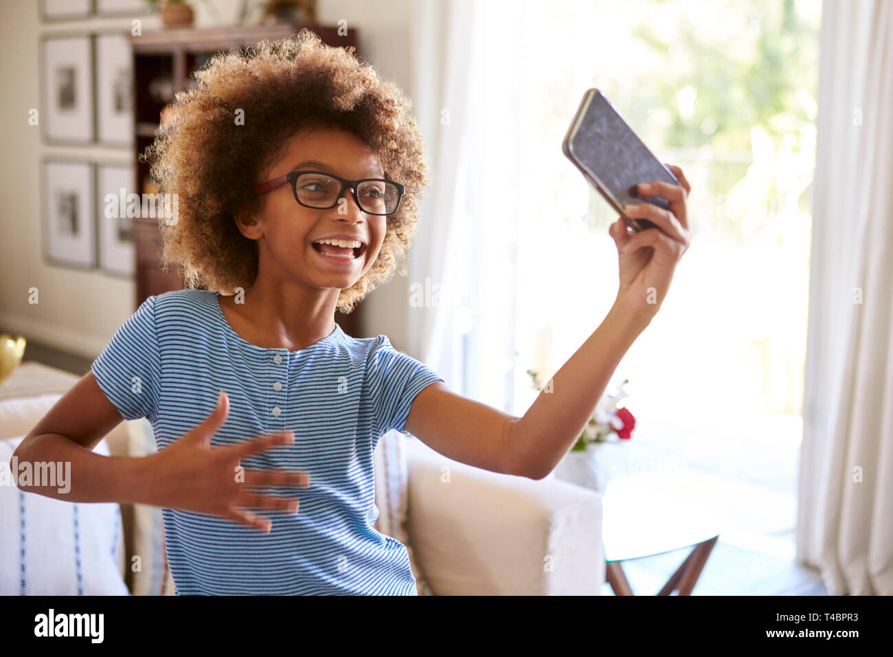 Pre-teen ragazza cattura se stessa cantando utilizzando un social media app sul suo smartphone, close up Foto Stock