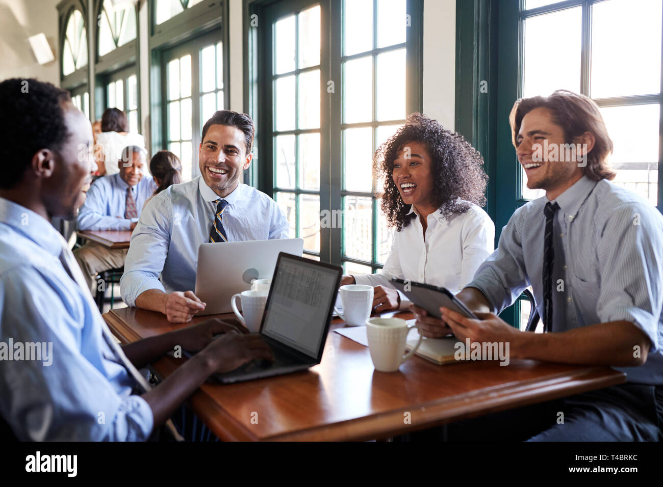 Team aziende aventi una riunione informale intorno al tavolo In Coffee Shop Foto Stock