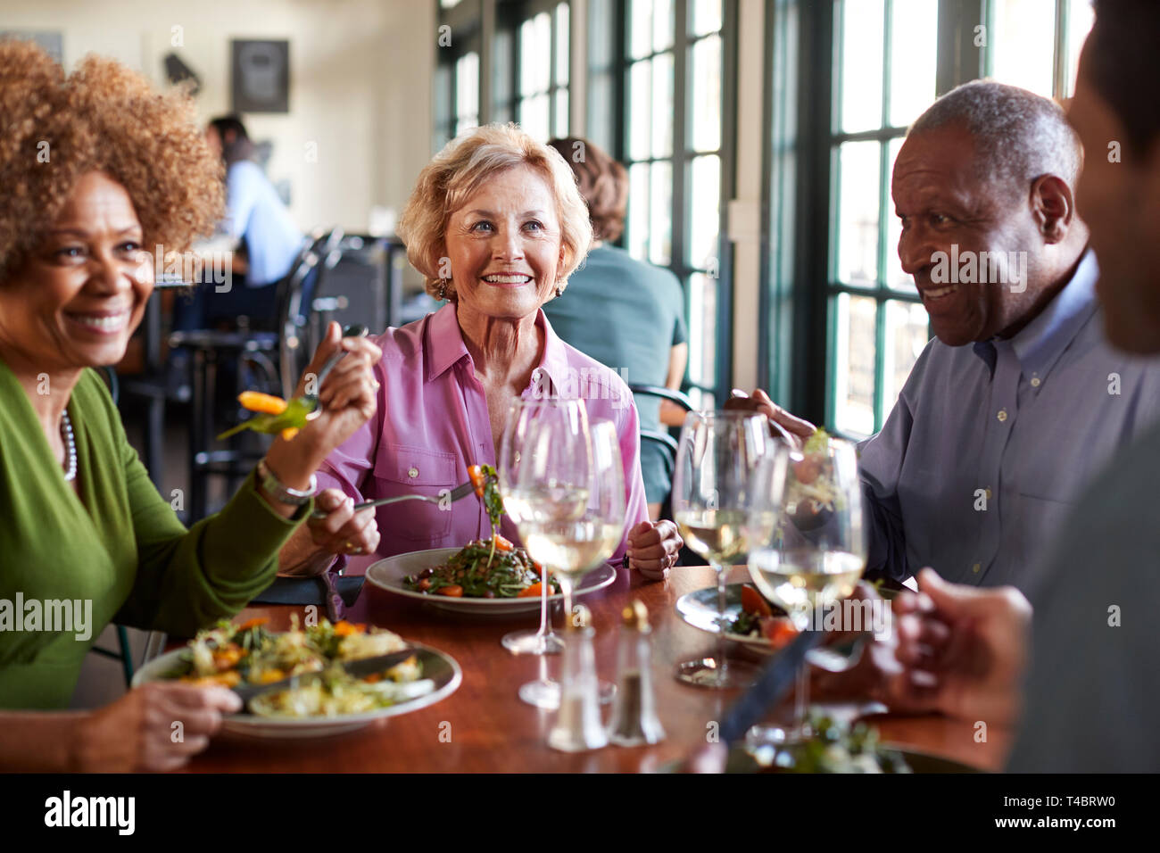 Gruppo di Senior sorridente amici riuniti per il pasto in ristorante Foto Stock