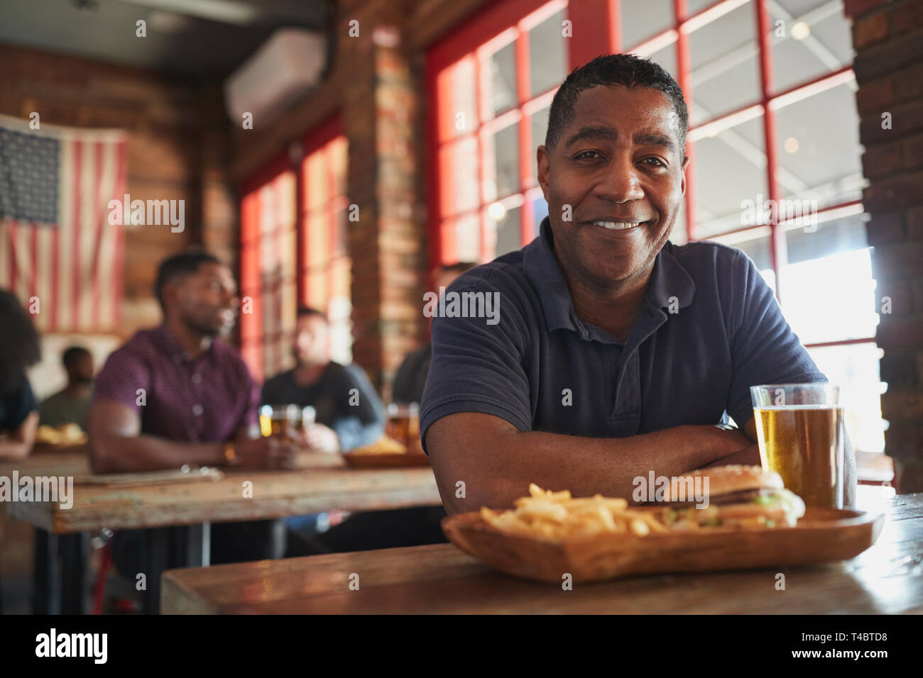 Ritratto di uomo nel Bar Sport di mangiare hamburger e patatine fritte Foto Stock