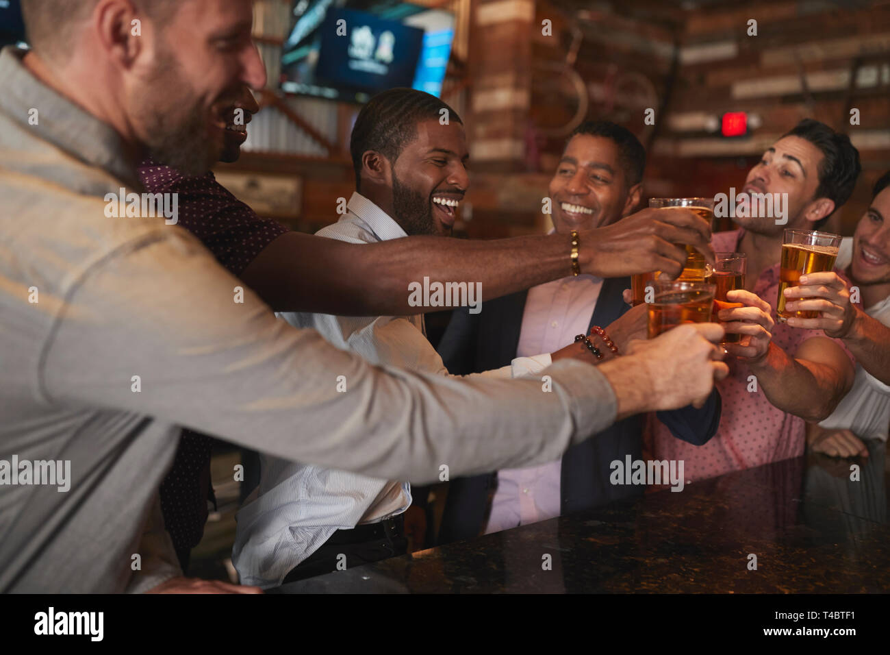 Gruppo di amici maschi sulla notte fuori per la festa di laurea in Bar rendendo brindare insieme Foto Stock