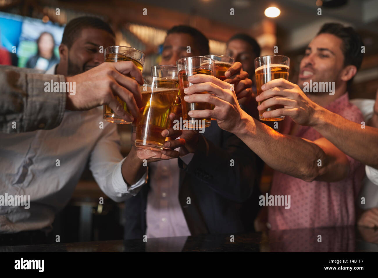 Gruppo di amici maschi sulla notte fuori per la festa di laurea in Bar rendendo brindare insieme Foto Stock