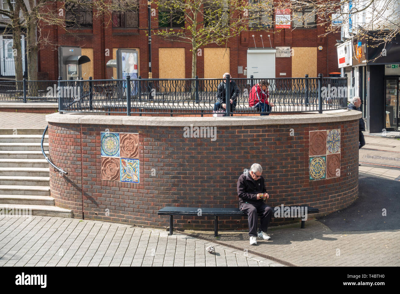 Persone sedersi nelle panche in George Street , Luton, Regno Unito Foto Stock