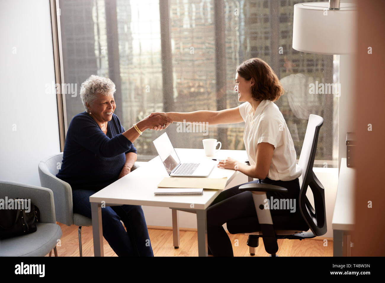 Senior donna stringono le mani con medico donna in ospedale Office Foto Stock