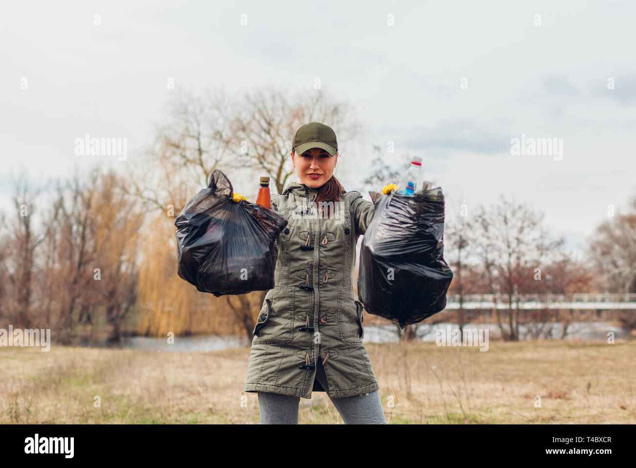 Donna volontario ripulito il cestino nel parco. Persone prelevati spazzatura e mostra il risultato con sacchi pieni. Ecologia e ambiente concetto. Sfida Foto Stock