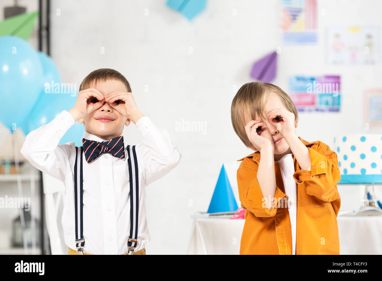 Adorabili preteen boys guardando telecamera attraverso le dita durante la festa di compleanno Foto Stock